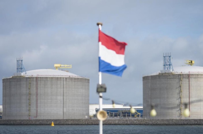 La bandera nacional holandesa ondea desde un barco turístico mientras los silos de gas natural licuado (GNL) se levantan en la costa en el puerto de Róterdam, Países Bajos. Foto: Forbes