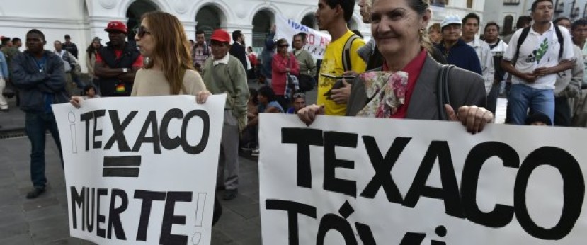 Activists holds signs reading 'Texaco = Death' and 'Texaco = Toxic' as they protest against US multinational energy corporation Chevron at a square in Quito on May 21, 2014. Lawyers for a group of Ecuadoran villagers are asking Canada's high court on Thursday to grant their clients access to Canadian courts to enforce a US$9.5-billion Ecuadorian judgment against Chevron Corp for rainforest damage. | RODRIGO BUENDIA via Getty Images