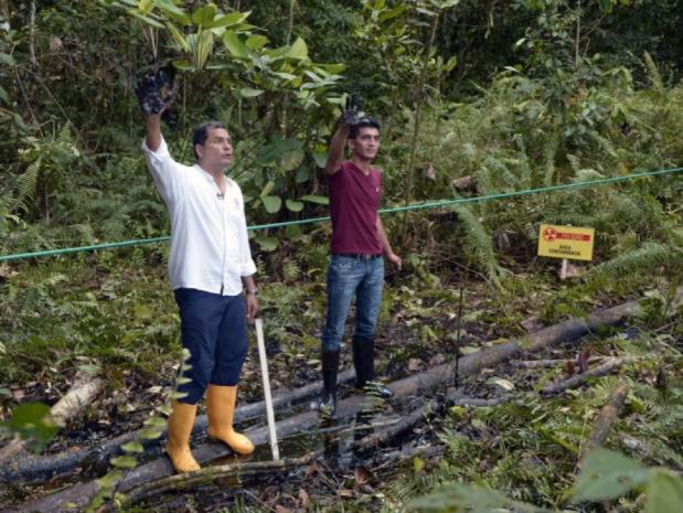 FOTOGRAFÍA AFP / RODRIGO BUENDIA El presidente ecuatoriano Rafael Correa y un habitante muestran sus manos cubiertas de crudo en el pozo Aguarico 4 en Aguarico, Ecuador, el 17 de septiembre de 2013.