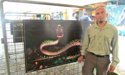 Darwin Núñez, junto a una fotografía de serpiente tomada en una de sus expediciones. Foto: La Hora