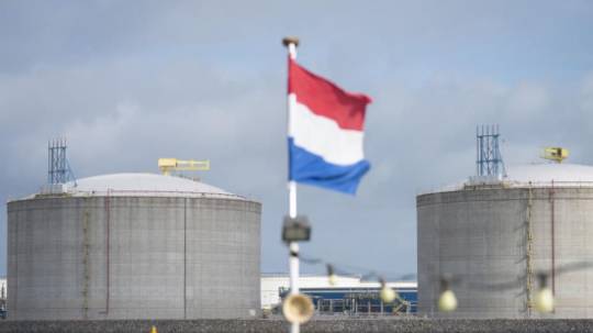 La bandera nacional holandesa ondea desde un barco turístico mientras los silos de gas natural licuado (GNL) se levantan en la costa en el puerto de Róterdam, Países Bajos. Foto: Forbes