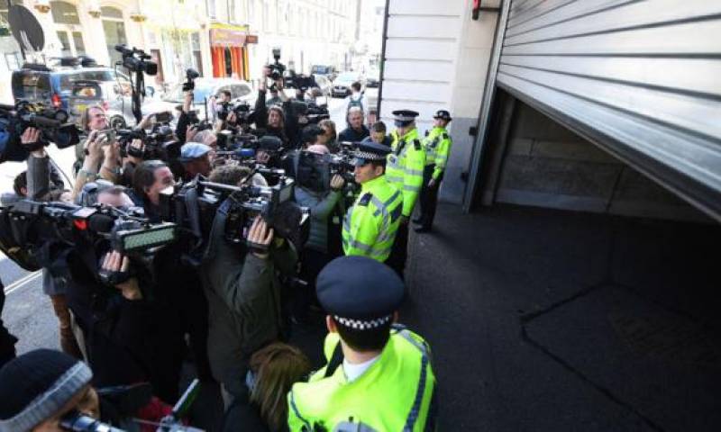 La policía hace un cordón de seguridad delante de varios reporteros para evitar que se acerque a un vehículo a las puertas del Tribunal de Westminster, este jueves 11 de abril, en Londres (Reino Unido). Foto: El Comercio